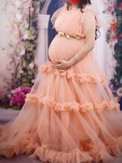 A lovely client glowing in my peach ruffle gown for her maternity photoshoot. The soft color and tiered ruffles create a dreamy, romantic effect that is perfect for studio sessions.
