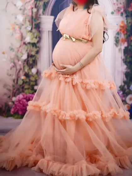 A lovely client glowing in my peach ruffle gown for her maternity photoshoot. The soft color and tiered ruffles create a dreamy, romantic effect that is perfect for studio sessions.