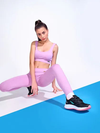 A dynamic shot for a women's sportswear and shoe campaign. The split-color background and the model's athletic pose create a visually interesting composition that is both fashionable and functional.