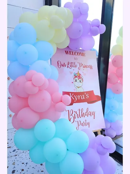 A pastel rainbow of balloons for Kyra's unicorn-themed birthday party. The personalized welcome sign sets a magical tone right from the start.