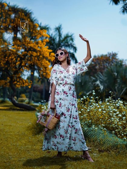 A full-length shot from the same series, where the model shields her eyes from the sun, adding a touch of playful glamour with her white sunglasses.