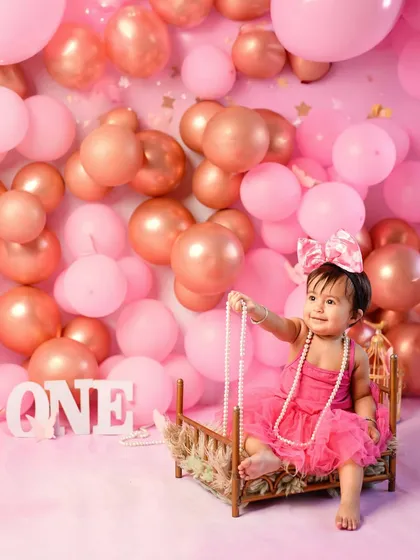 A little princess on her throne. Using our miniature bed prop, this one-year-old looks perfectly regal amidst a sea of pink balloons and pearls.