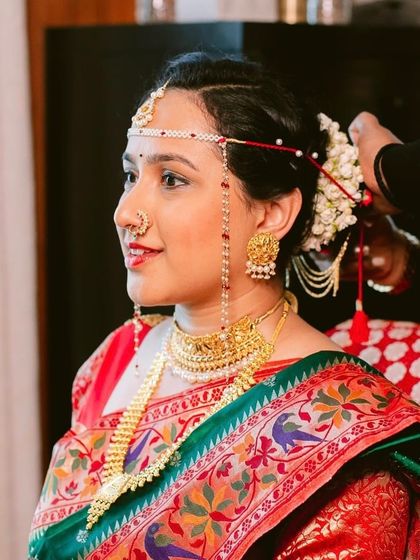 Our hairstylist carefully places flowers into a traditional bridal bun. This classic Maharashtrian hairstyle is elegant and securely holds the intricate jewelry and accessories.