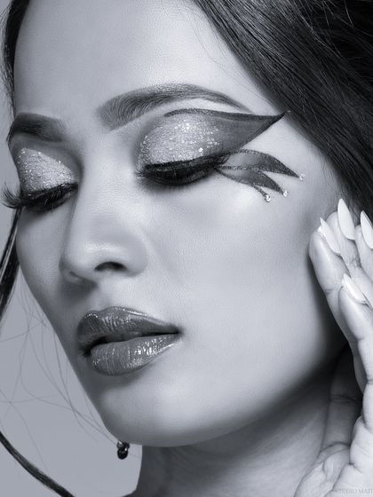A black and white version of a creative beauty portrait. The monochrome style emphasizes the shape and texture of the graphic eyeliner.