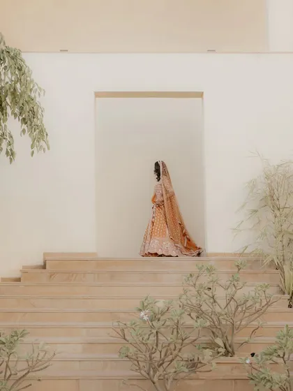 The bride walking up the stairs, her beautiful lehenga trailing behind her. This is a graceful and elegant shot that feels like a painting.