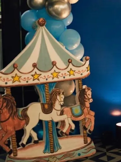 The hand-painted carousel prop adds a touch of vintage charm and whimsy to the royal blue birthday setup.