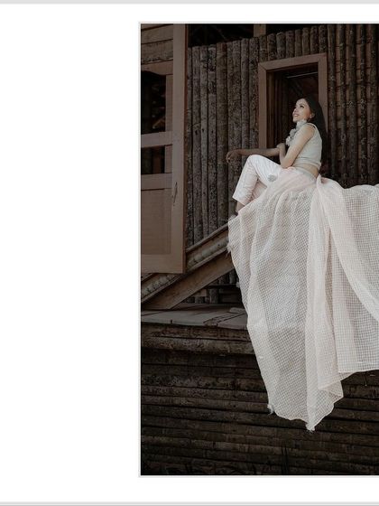 A beautiful, elegant portrait of the bride to be during her pre-wedding shoot. The way her white skirt drapes over the rustic wooden steps creates a stunning visual.