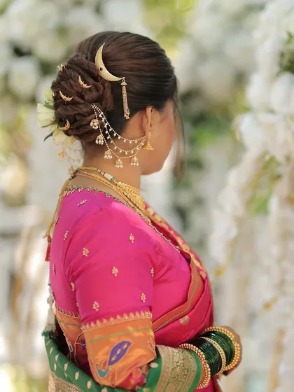 The details make the look complete. This intricate bridal bun, adorned with a traditional Maharashtrian crescent moon accessory, is the perfect finishing touch for a royal Nauvari look.