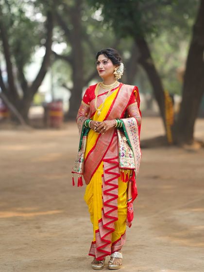 A full-length shot of the bride in her yellow Nauvari, set against a rustic backdrop.