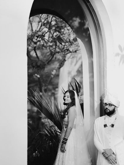 A beautiful black and white portrait using an archway to frame the couple. The contrast between light and shadow adds a dramatic and romantic feel.