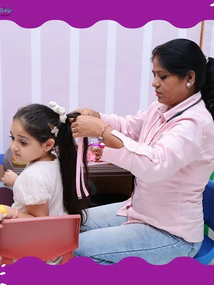 A stylist carefully braids a young girl's hair, adding colorful ribbons to complete the look.