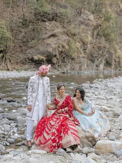 A beautiful portrait of the bride and groom with their sibling, a cute trio enjoying a moment together by the river in Rishikesh.