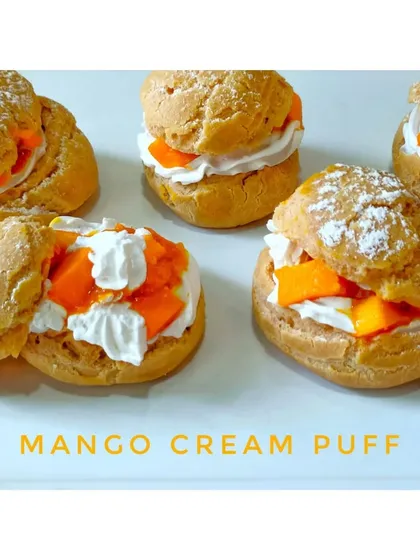 A collection of my Mango Cream Puffs. I make the choux pastry from scratch, ensuring it's light and crisp, the perfect vessel for the creamy mango filling.