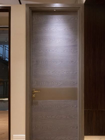 A modern door made from grey-toned wood veneer with a central metal band. This design is understated yet sophisticated, perfect for a minimalist interior.