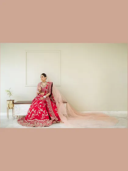 A wide shot of the bride, Varsha, seated elegantly, her long, flowing dupatta creating a beautiful trail. This composition emphasizes the grandeur of her bridal lehenga.