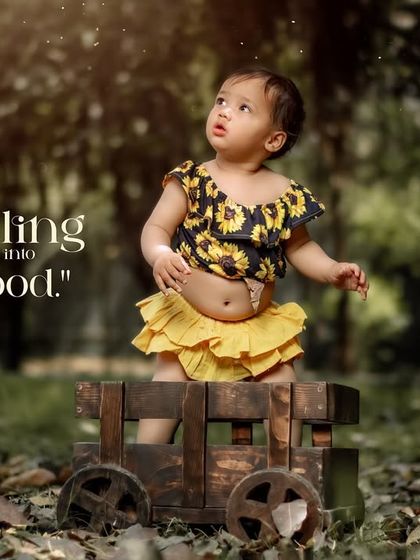 Sprinkling a little magic into childhood. A girl in a bright yellow outfit stands in her wooden wagon in a mystical forest.