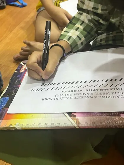 Focus and precision. A student carefully practices straight-line strokes, an essential exercise in our beginner calligraphy lessons.