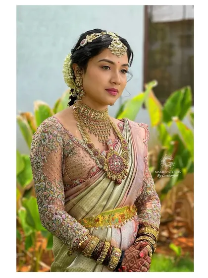 A bride in a pastel toned Kanjivaram saree with a fully embroidered illusion long sleeve blouse. This design blends traditional fabric with a contemporary silhouette for a truly unique bridal look.