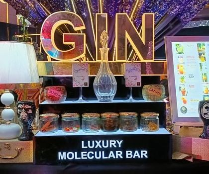 A dedicated gin tasting station, complete with a variety of botanicals in glass jars for guests to explore, flanked by digital menus.
