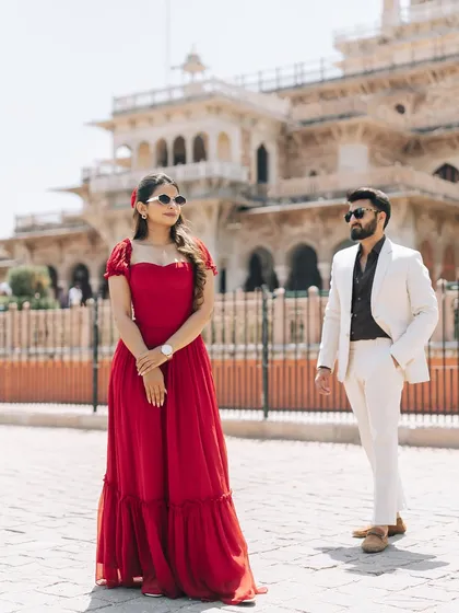 A stylish pose in front of the Albert Hall Museum in Jaipur. The contrast of the modern red dress and white suit against the Indo-Saracenic architecture creates a striking, fashionable pre-wedding photograph.