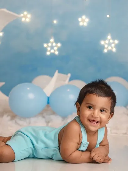 Over the moon for this little star. A happy baby enjoys tummy time on a fluffy cloud under a sky full of twinkling stars.