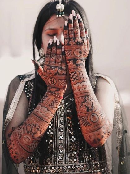 A beautiful photo of the bride with her hands covering her face, showcasing the full extent of her stunning bridal mehndi.