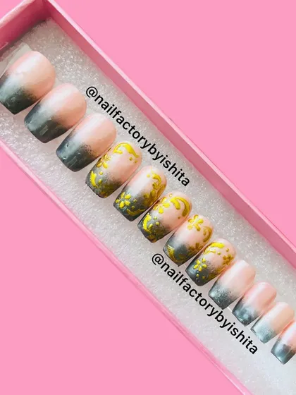 A set of custom press-on nails featuring a black and grey ombre with gold chrome art.