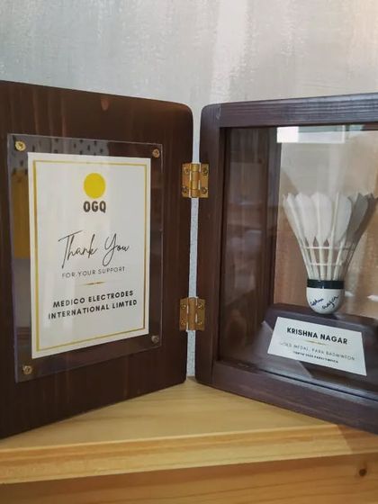 The open shadow box, showing the "Thank You" message on the inside of the door and the autographed shuttlecock displayed with reverence.