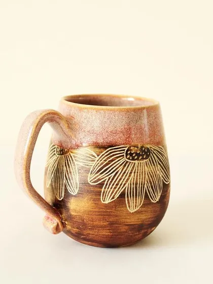 The Pink Sienna mug showcases a beautiful contrast I love to play with. A glossy, rosy pink glaze meets a rustic, earthy finish, with delicate flowers I carve by hand to reveal the clay beneath.