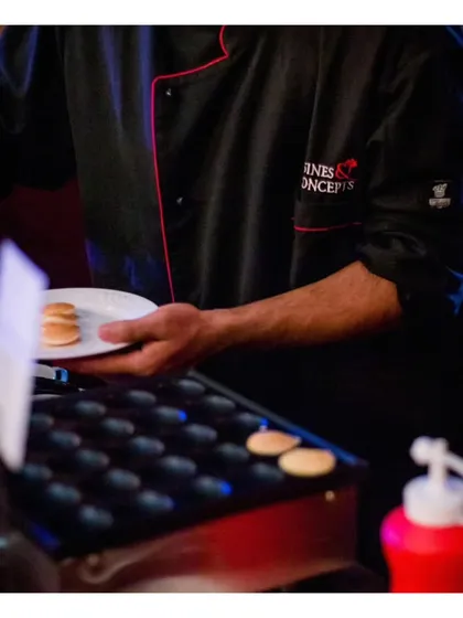 A chef prepares mini pancakes on a specialized griddle. This highlights our ability to offer unique dessert or breakfast items at live stations, adding a novel touch to the menu.