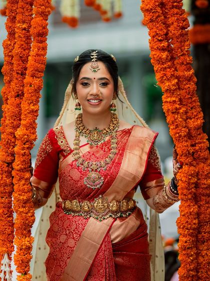 A beautiful portrait of the bride framed by marigold garlands, her red saree and radiant makeup glowing.