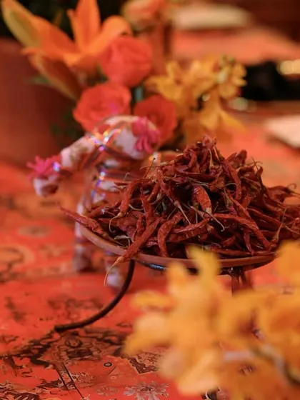 A small, whimsical cart figurine carrying a bowl of dried red chilies, adding a playful and spicy touch to the table decor.