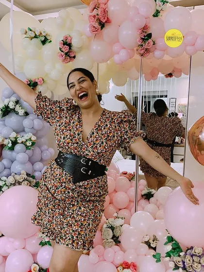 A joyful birthday celebration with a backdrop of pastel pink and white balloons mixed with florals. This kind of setup creates a soft and dreamy atmosphere perfect for milestone photos.