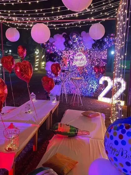 I can create a full party atmosphere outdoors, like this 22nd birthday cabana setup. It includes fairy light curtains, a shimmer wall backdrop, a neon sign, and marquee numbers, along with comfortable seating for guests.