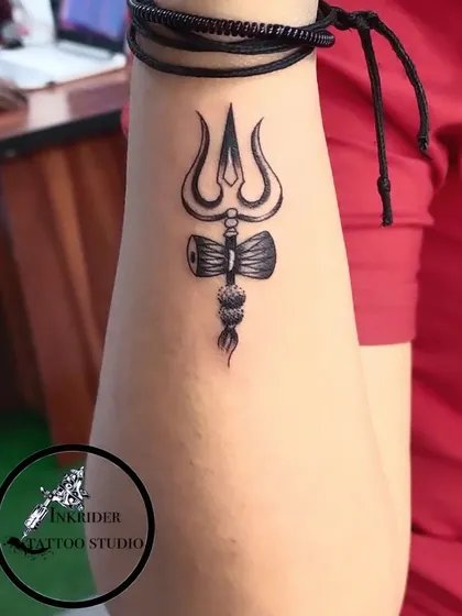 A powerful Trishul and Damru tattoo on the forearm, symbolizing the divine power of Lord Shiva.