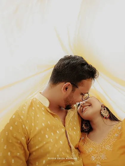 An intimate portrait under a flowing yellow dupatta, creating a soft and romantic frame for the couple's pre-wedding photo.