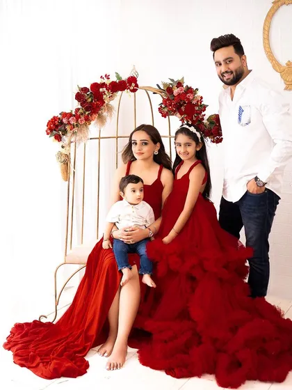 A beautiful, formal family portrait. The coordinated red and white outfits, combined with the elegant studio setup, create a picture-perfect image.
