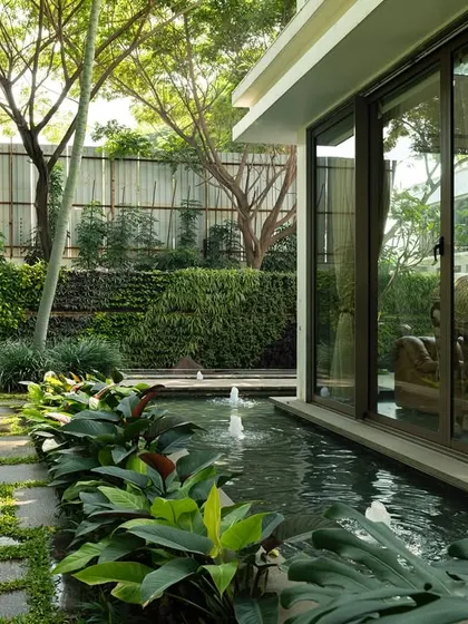 A view from inside a home, looking out past a wooden horse sculpture to the garden and water feature. The design layers art, architecture, and landscape to create a rich and immersive experience.
