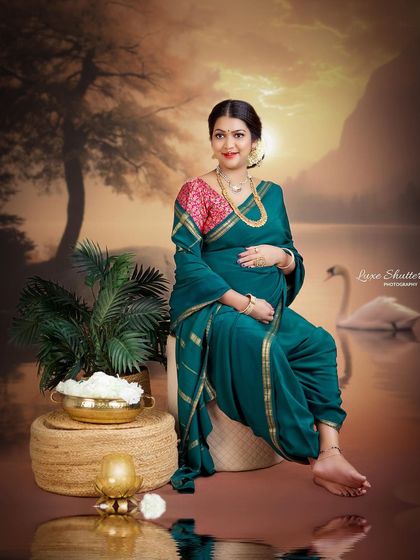A serene portrait of a mother-to-be in a traditional green 'nauvari' saree. The setting, with its warm tones and props, evokes a sense of calm and heritage.