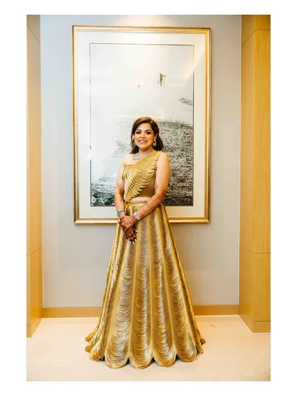 The bride, looking radiant in her golden gown, ready for her Sangeet night. Her elegant outfit is perfect for a night of dancing and celebration.