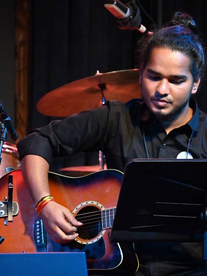 An acoustic guitarist providing the rhythmic foundation during a band performance. Our lessons cover a wide range of guitar skills, from fingerstyle to strumming patterns.