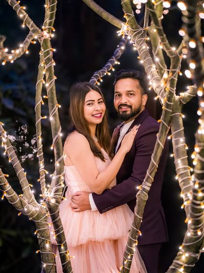 A glamorous couple poses amidst the fairy-lit trees, a perfect example of an elegant night-time portrait.
