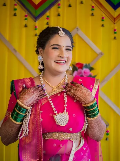A portrait of a woman's pure, uninhibited laughter during a traditional celebration. Her vibrant pink saree, intricate pearl jewelry, and henna-adorned hands showcase the rich cultural details I love to capture.