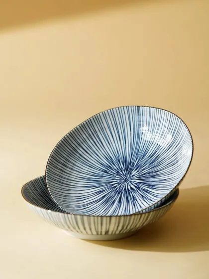 A clean, minimalist shot of two patterned ceramic bowls, using hard light and shadows to emphasize their shape and design.