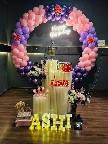 A grand ring decoration with multiple plinths for props and cake. This setup uses a full balloon circle and marquee letters to create a stunning centerpiece.