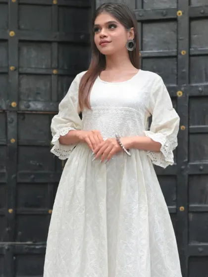 An elegant white-on-white embroidered dress with detailed lacework on the sleeves. This is a beautiful and graceful piece that is perfect for daytime events.
