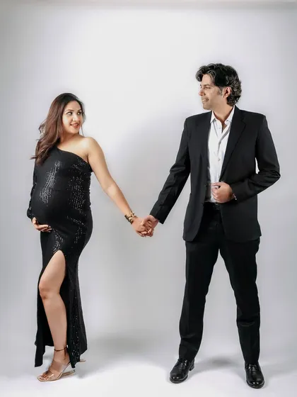 A joyful and connected portrait of an expecting couple holding hands in the studio. Their smiles and gaze towards each other perfectly capture their partnership on this journey.