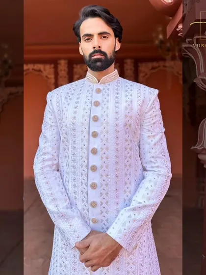 A detailed portrait shot of a groom in our white embroidered sherwani. The mandarin collar and precise fit give it a sharp, regal appearance.