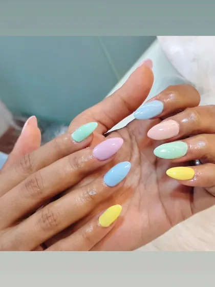 A playful pastel rainbow manicure. Each nail is a different soft color, creating a fun and cheerful look.