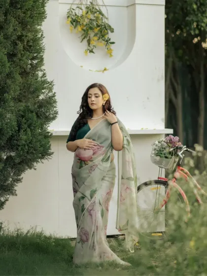 Elegance in the garden. The mother-to-be looks serene and beautiful in a floral print saree, with a flower in her hair, creating a picture of natural grace and timeless style.